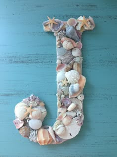 the letter j made out of seashells and starfish on a blue background