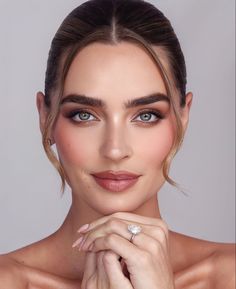 a beautiful woman with blue eyes wearing a ring and holding her hand on her chest