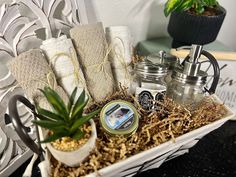 a white basket filled with towels and other items next to a potted succulent