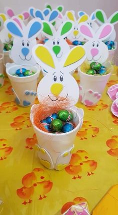 an easter table with bunny ears, eggs and candy in buckets on top of the table