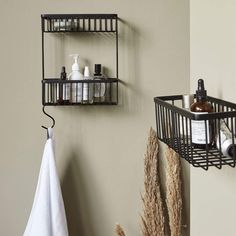 two black metal shelves with soap and lotion on them next to a towel rack