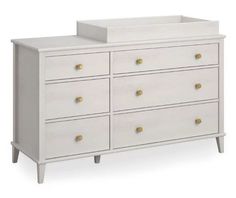 a white dresser with gold knobs and drawers on the bottom drawer, against a white background