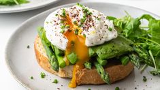 an open face sandwich with lettuce and sour cream on top, sitting on a plate