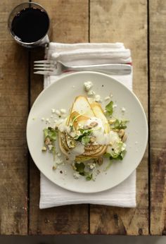 a white plate topped with food next to a cup of coffee on top of a wooden table