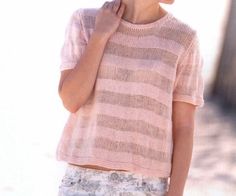 a woman in pink sweater and floral shorts holding a cell phone to her ear while standing on the street