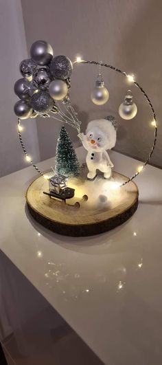 a snowman on a wooden board with christmas balls and lights in the shape of trees