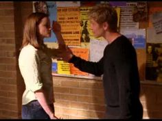 a man standing next to a woman in front of a bulletin board