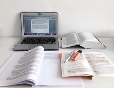 an open book sitting on top of a desk next to a laptop computer and pen