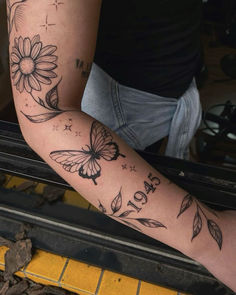 a woman's arm with flowers and butterflies tattooed on the back of her arm