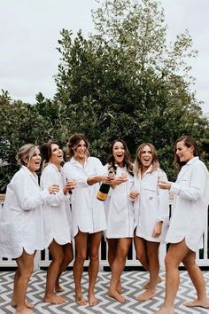 a group of women in white robes standing next to each other on a deck with drinks