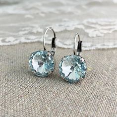 "Heatherly Designs dangling leverback earrings made with a rivoli cut Swarovski crystal set in solid brass lever back earrings plated in your choice of precious metal finish. Shown in a pale icy blue and aged silver. ●Nickel free ●Size (L x W): 7/8\" x 1/2\" or 22 x 12mm ●Swarovski crystal color(s): Light Azore ●Arrives in our signature Heatherly gift box. Handmade with ❤ by Heather ● ● ● ● ● ● ● ● ● ● ● ● ● ● ● ● ● ● ● ● ● ● ● ● ● ● ● ● →Quantity Discounts listed below: 10% off 3-6 pcs - 10OFF3 Blue Earrings Wedding, Jewelry Portfolio, Gift Box Handmade, Earring Pins, Blue Crystal Earrings, Wedding Vision, Etsy Bridesmaid Gifts, Earrings Simple, Leverback Earrings