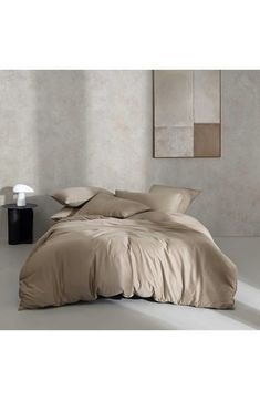 an image of a bed that is made up with beige sheets and pillowcases