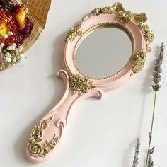 a pink vanity mirror sitting on top of a table next to flowers and a vase