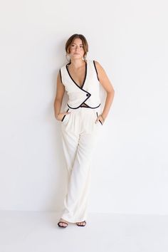 Get ready to stand out in style with The Elena Set! The sleeveless vest features V-neckline and a double-breasted design with a button closure for a sophisticated look. The adjustable back tie and cream and black contrasting edges make this vest a true statement piece. Pair it with the matching pants for a chic look. Details + Fit 100% Polyester Runs True to Size Hand Wash Cold Hang Dry V-Neckline Sleeveless Double Breasted Button Closure Adjustable Back Tie High Waist Button Closure Belt Loop S Chic V-neck Vest For Daywear, Chic V-neck Vest For Day Out, Chic Loungewear Pantsuit, Elegant Sleeveless Blouse Vest For Day Out, Elegant Sleeveless Vest For Day Out, Sleeveless Fitted Spring Pantsuit, Fitted Sleeveless Spring Pantsuit, Fitted Sleeveless Pantsuit For Spring, Casual Fitted Sleeveless Pantsuit