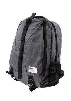 a gray backpack with black straps on the front and back sides, sitting against a white background