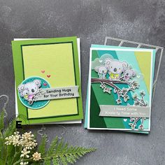 two cards with koalas on them sitting next to some plants and flowers in vases