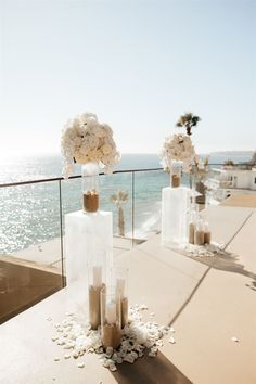 a table with flowers and candles on it near the ocean