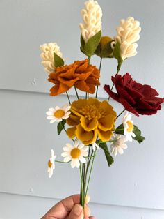 a hand holding a bunch of fake flowers