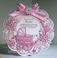 a pink and white card with a baby carriage on it's side, surrounded by flowers