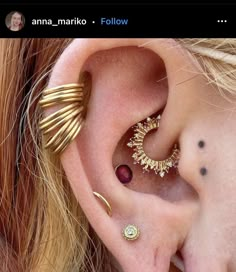 an ear with three different types of piercings on top of it, and the bottom one is gold