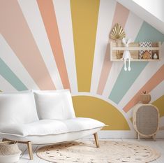 a white couch sitting on top of a rug next to a wall painted in pastel colors