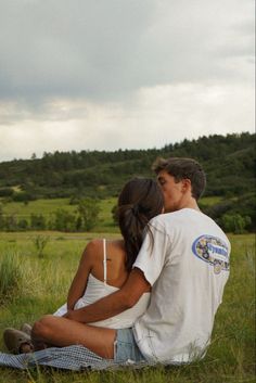 a man and woman sitting in the grass