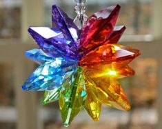 a multicolored glass star ornament hanging from a window sill in front of a brick building