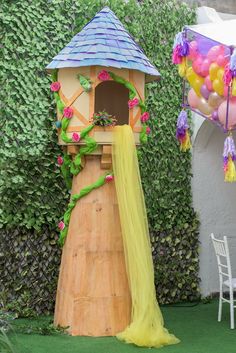 a birdhouse with flowers and vines on the roof is next to a white chair