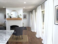 a living room filled with furniture and a fire place next to a white brick wall