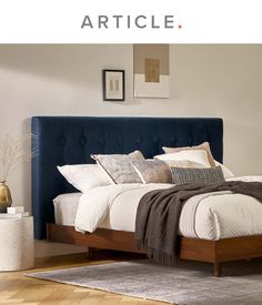 a large bed sitting on top of a wooden floor next to a white and gray wall