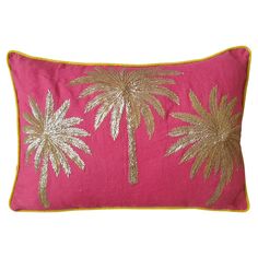 a pink pillow with gold palm trees on it