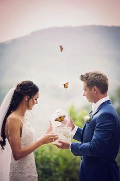 the bride and groom are exchanging their wedding vows in front of butterflies flying above them