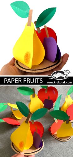 an apple and pear cut out from paper on top of a wooden plate with leaves