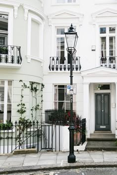 a street light sitting in front of a white building with black balconies on it