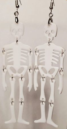 Hand-crafted Pierced Earrings Unique and One-of-a-Kind Skeleton Earrings Approximately 3-3/4" long x 1-1/8" wide Featuring resin skeleton bones, hand-assembled with stainless jumping. They are lightweight and elegant and are set with high quality, stainless, hypoallergenic, ear wires. Carded. Made in a clean, smoke free, pet free and temperature controlled studio. Ready to ship immediately. Halloween Skull Jewelry In Bone Color, Halloween Skull Shaped Bone Jewelry, White Gothic Handmade Earrings, Handmade White Gothic Earrings, White Skull-shaped Halloween Jewelry, Halloween Skull Jewelry In White, White Skull Jewelry For Halloween, Halloween White Skull Jewelry, White Skull Jewelry For Day Of The Dead