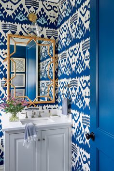 a bathroom with blue and white wallpaper, a mirror and sink in the corner