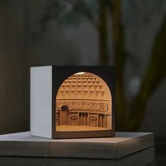 a lit up building with an arch in the middle on a table next to a potted plant