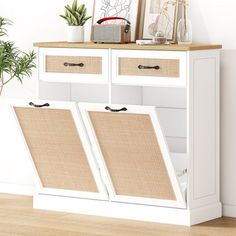 a white cabinet with two baskets on top of it and a plant next to it