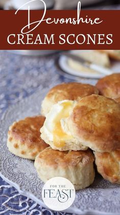 some biscuits with butter on top are sitting on a blue lace tablecloth and there is a text overlay that reads, deonine cream scones for the feast