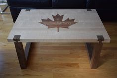 a wooden table with a maple leaf design on the top, sitting in front of a black couch