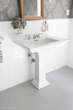 a white bathroom sink sitting under a mirror next to a wall mounted faucet