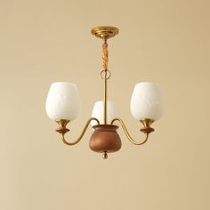 an antique brass chandelier with two white glass shades hanging from it's arms