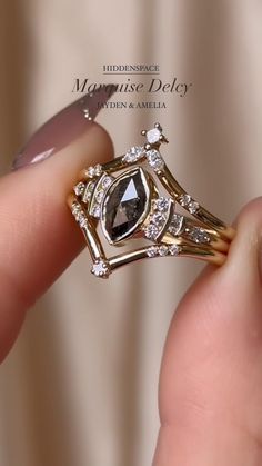 a close up of a person's hand holding a gold ring with a black diamond