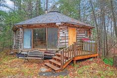 a small cabin in the woods with stairs leading up to it's door and porch