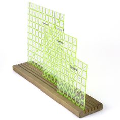 three pieces of green paper sitting on top of a wooden stand with squares and lines