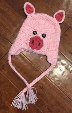 a crocheted pig hat with tassels on the bottom and ears is laying on a wooden floor