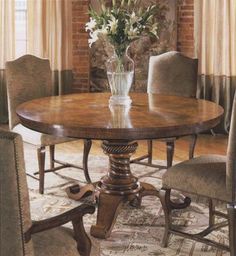 a dining room table with chairs and a vase filled with flowers on top of it