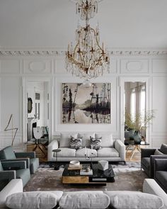 a living room filled with lots of furniture and a chandelier hanging from the ceiling