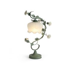 a lamp that is on top of a stand with flowers and leaves around the base