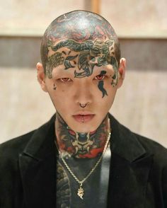 a young man with tattoos on his face and neck is looking at the camera while wearing a black jacket